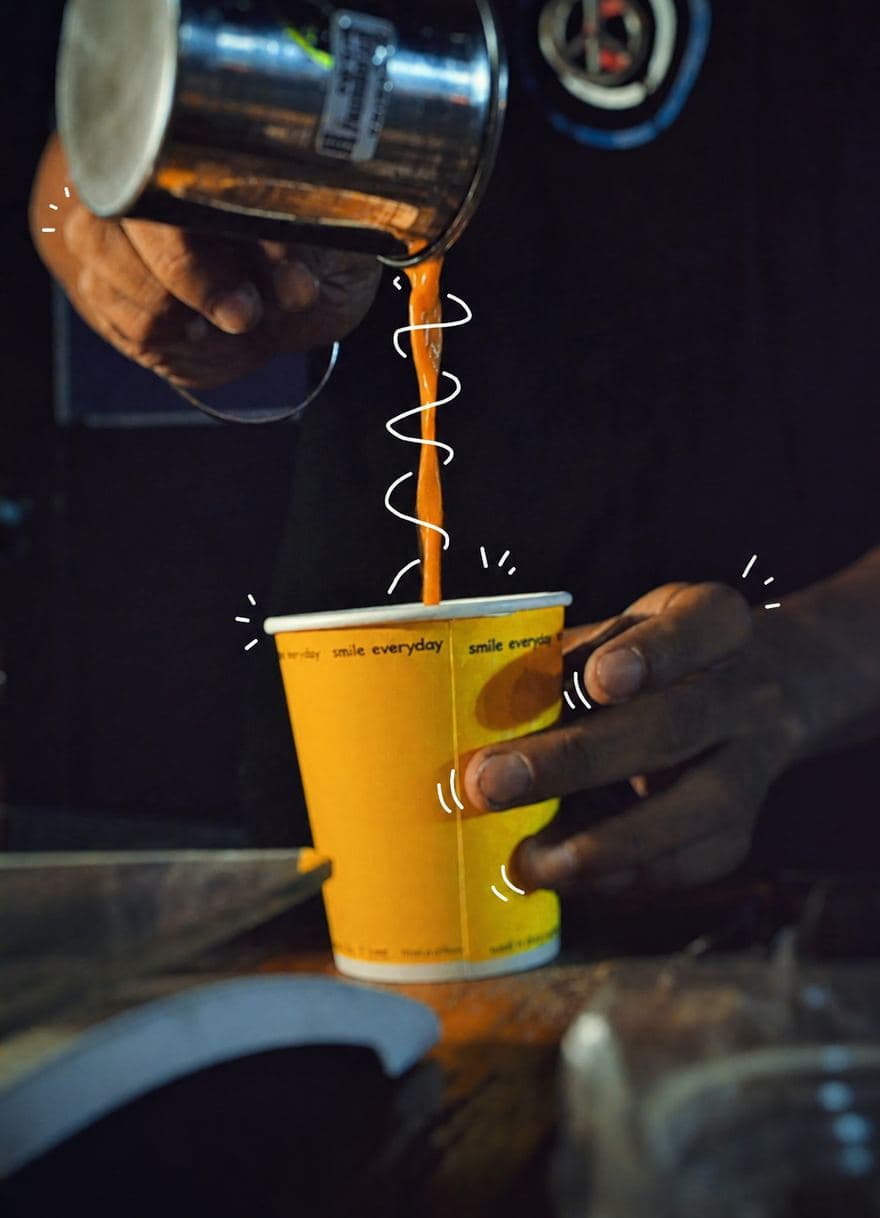 Coffee poured from a jug into a bright yellow takeaway cup